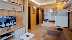 A modern kitchen with a microwave, a small table, and a TV displaying a boxing match. - Wooden Accent 2Br At Mekarwangi Square Cibaduyut Apartment (Bandung)
