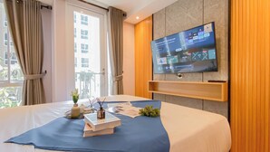 Una camera d'albergo moderna con un letto grande, una TV a parete e vista sulla città dalla finestra.