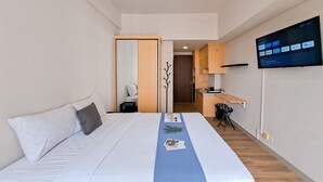 Une chambre d’hôtel moderne équipée d’un lit, d’un bureau et d’un téléviseur affichant une interface numérique.