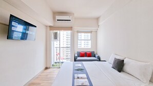 Une chambre d’hôtel moderne dotée d’un grand lit, d’un téléviseur à écran plat fixé au mur et d’un balcon offrant une vue sur la ville.