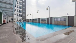 An indoor swimming pool with clear water, surrounded by a tiled deck and a building with balconies. - Modern And Comfy 2Br Apartment Mekarwangi Square Cibaduyut (Bandung)