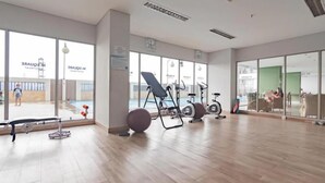 A spacious gym with exercise equipment, large windows, and a view of the outside. - Modern And Comfy 2Br Apartment Mekarwangi Square Cibaduyut (Bandung)