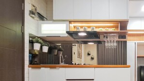 A modern kitchen with white cabinets, a wooden countertop, and a built-in wine rack. - Modern And Comfy 2Br Apartment Mekarwangi Square Cibaduyut (Bandung)