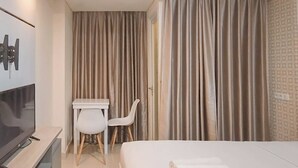 Une chambre d’hôtel avec un lit, une télévision, un bureau avec une chaise et des rideaux.