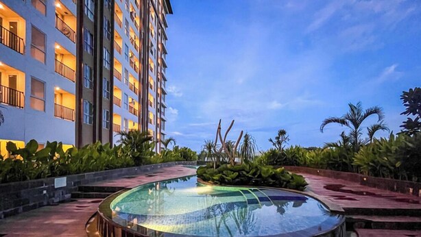 Un hôtel doté d’une piscine circulaire, entourée de plantes tropicales et de palmiers.