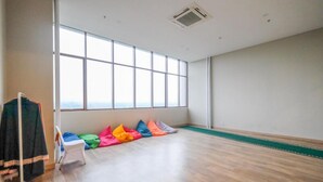 A spacious room with large windows, a wooden floor, and colorful pillows arranged in a row. - Modern Style Studio Apartment At Royal Sentul Park (Bogor)
