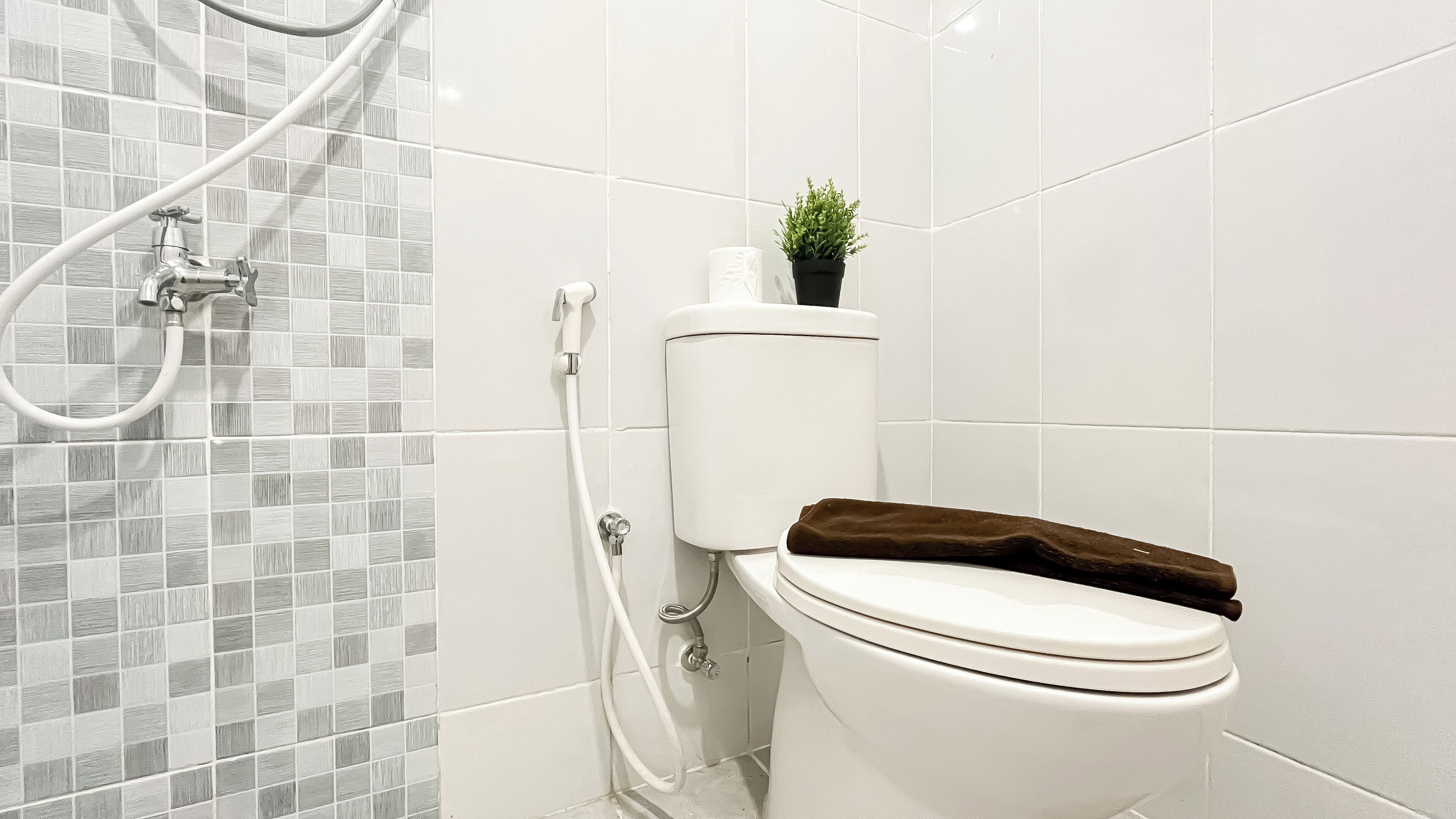 Une salle de bain avec des toilettes, une douche et un mur carrelé.