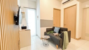 Een moderne woonkamer met een bank, een klein rond bijzettafeltje en een televisie.