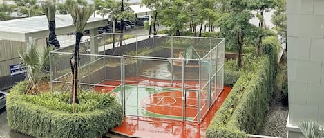 Un terrain de basket entouré d’une clôture métallique, avec des marches menant au terrain.
