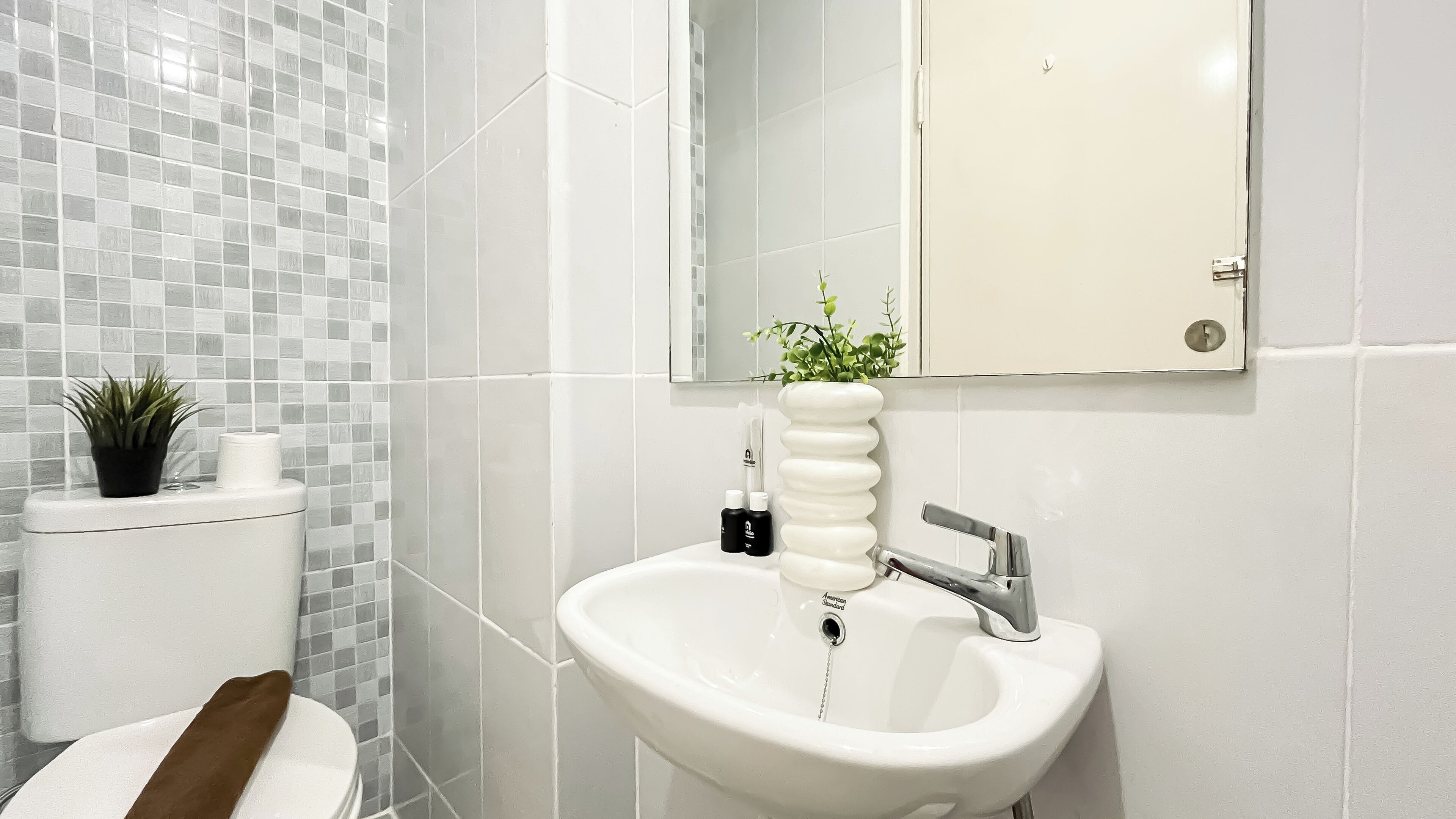 A bathroom with a white sink, a toilet, and a mirror.