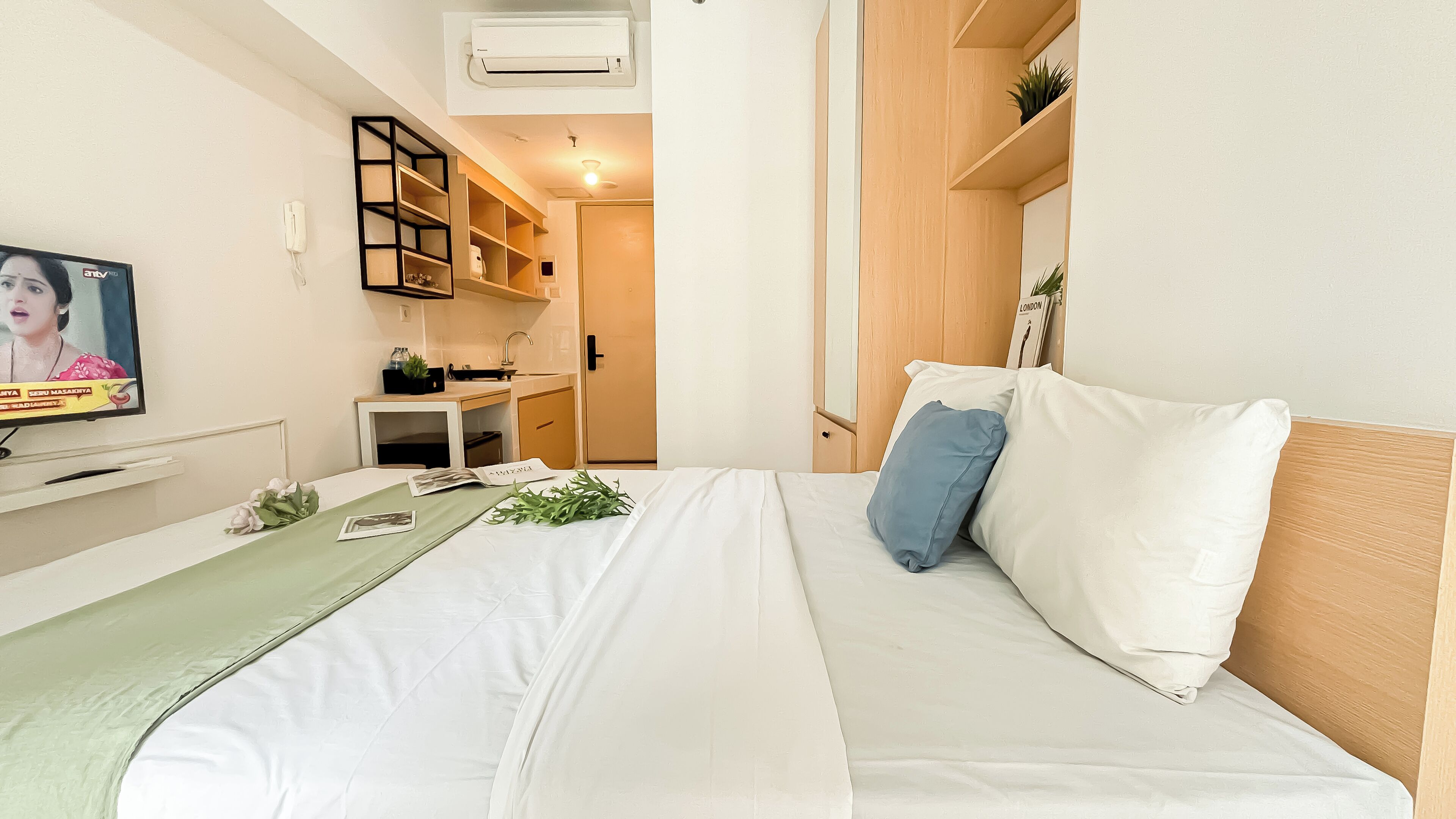 Un dormitorio con cama, televisión, escritorio y armario.