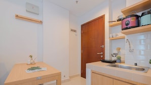 A compact kitchen with a wooden countertop, a built-in sink, and a wooden door. - Strategic And Spacious 2Br At Capitol Park Residence Apartment (Jakarta)