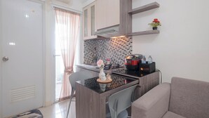A compact kitchenette with a dining area, a sofa, and a potted plant. - Strategic 2Br Apartment At Green Pramuka City (Jakarta)