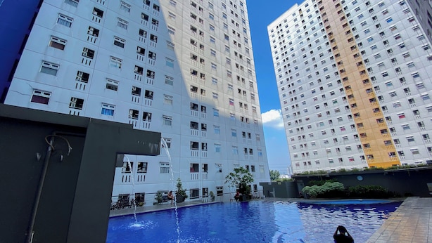 A residential building with a swimming pool, multiple balconies, and a clear sky. - Strategic 2Br Apartment At Green Pramuka City (Jakarta)