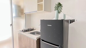 A kitchen with a black refrigerator, a gas stove, and a sink. - Trendy 1Br Apartment At Vittoria Residence (Jakarta)