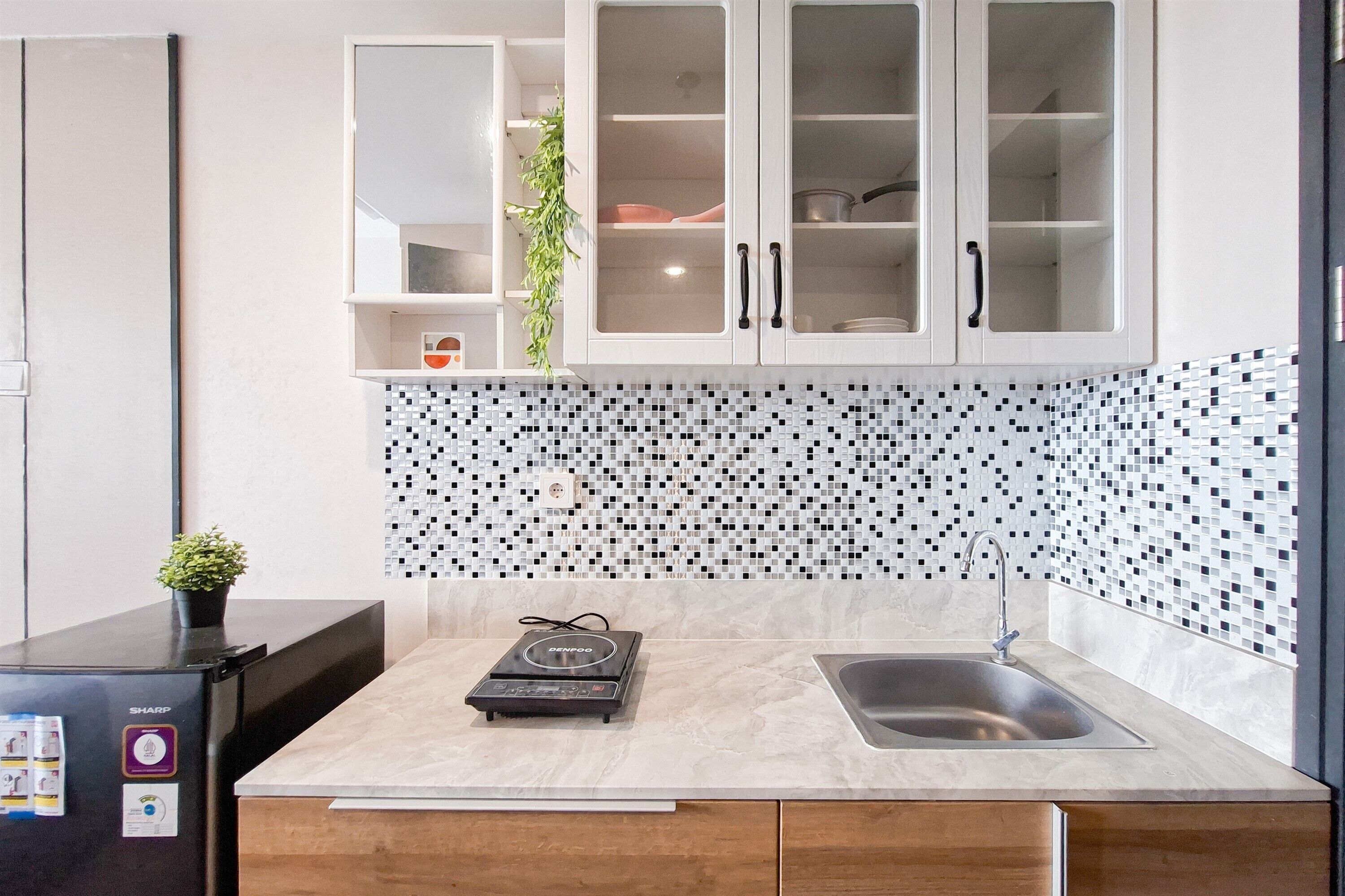 Eine moderne Küche mit Marmorarbeitsplatte, integriertem Spülbecken und einem Sharp-Kühlschrank.