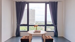 Een kamer met een groot raam, een ronde tafel met een bloevas en twee comfortabele stoelen.