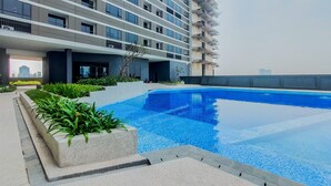 Een modern gebouw met een zwembad, omringd door groen en een heldere lucht.