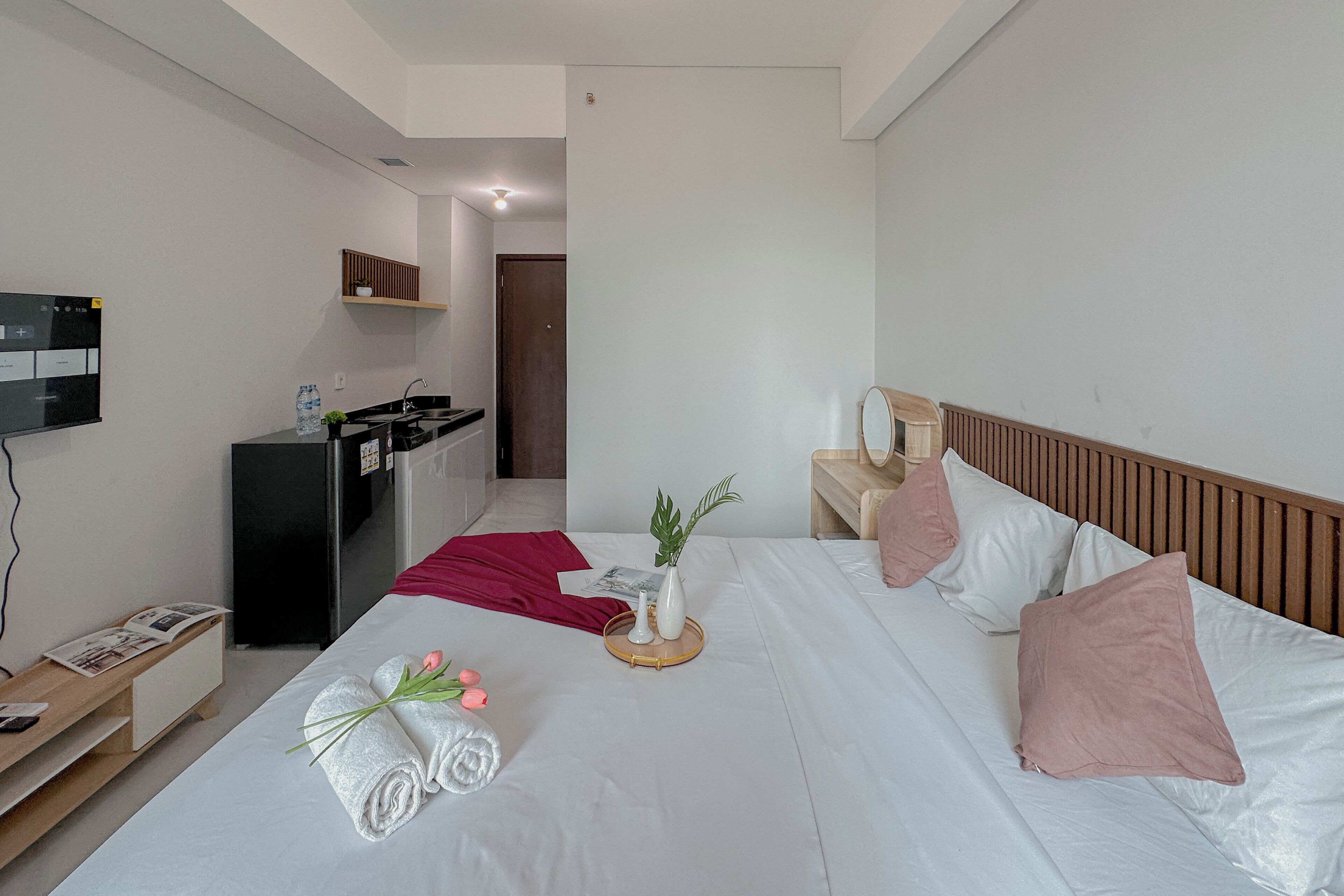 Een hotelkamer met een bed, een bureau, een televisie en een kitchenette.