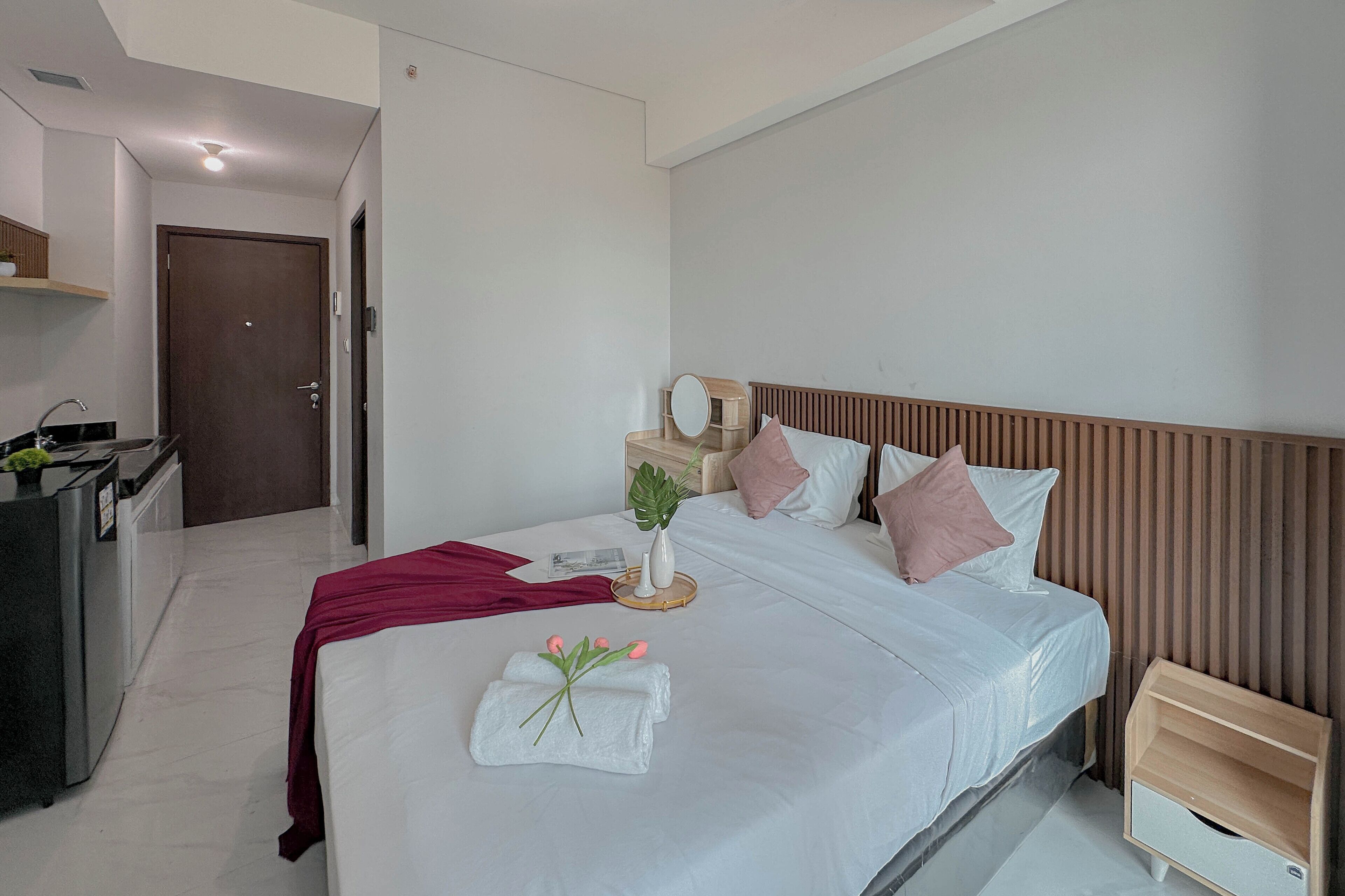 Una habitación de hotel con cama, mesita de noche y un escritorio pequeño con espejo.