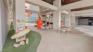 A modern indoor playground area with a sign reading "Caribbean Playground," featuring a large slide and play structures. - Simple Studio At The Trans Icon Surabaya Apartment (Surabaya)