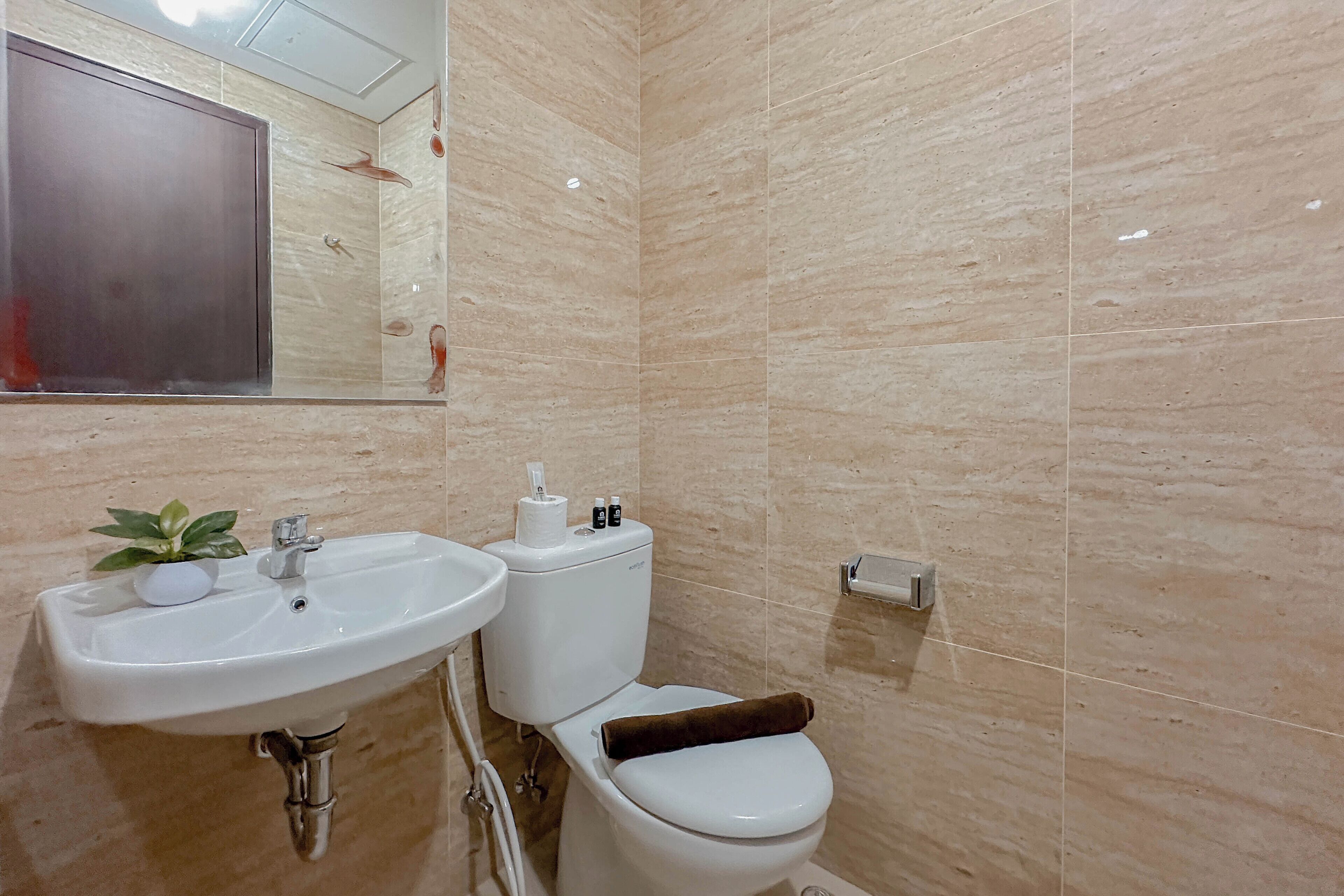 A bathroom with a sink, toilet, and mirror.