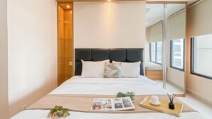Une chambre moderne avec un grand lit, un mur recouvert de panneaux en bois et une grande fenêtre.