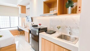 Une cuisine moderne équipée d’un four, d’un micro-ondes et d’un évier intégrés. On y trouve également un coin repas avec une table et des chaises, ainsi qu’une fenêtre offrant une vue sur la ville.