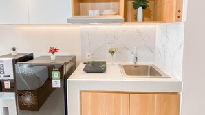Une cuisine compacte équipée d’un four à micro-ondes encastré, d’un évier et d’un plan de travail agrémenté d’une petite plante.