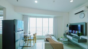Ein modernes Wohnzimmer mit Essbereich, einer Couch, einem Fernseher und einem großen Fenster.