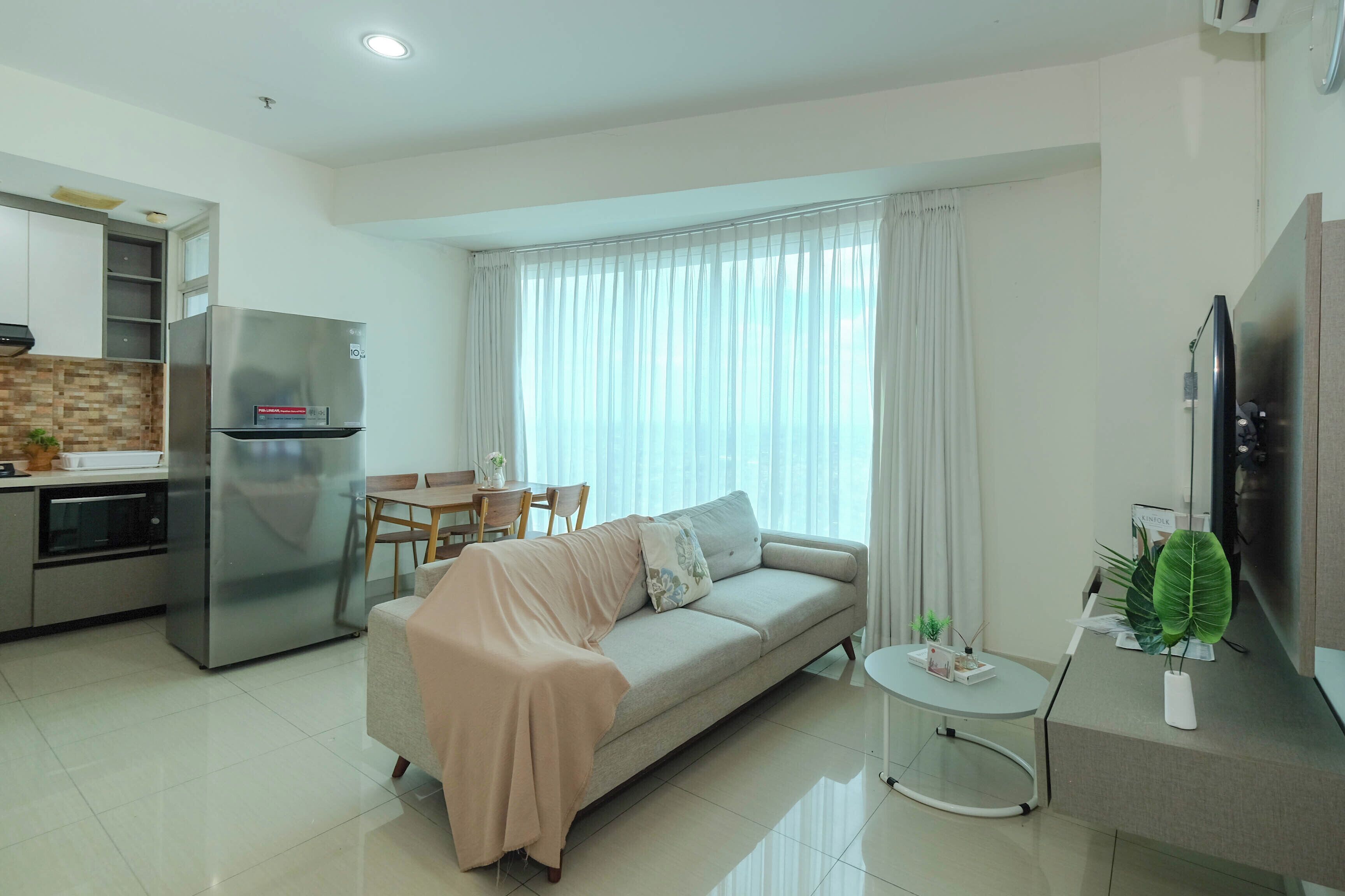 Una sala de estar moderna con un sofá, una mesa de comedor y una zona de cocina que incluye un refrigerador y un horno.