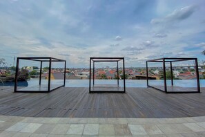 A rooftop terrace with a wooden deck and three glass-enclosed structures. - Spacious 2Br Near Mall At Grand Kamala Lagoon Apartment (Bekasi)