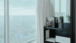 Ein modernes Zimmer mit einem großen Fenster, einem Schreibtisch mit einem Laptop, einer Topfpflanze und einem Buch mit dem Titel "KINELIK".