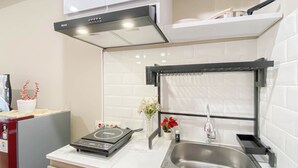 A modern kitchen with a built-in stove, a stainless steel sink, and a black range hood. - Cozy And Best Place Studio Apartment Royal Sentul Park (Bogor)