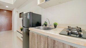 A modern kitchen with a built-in sink, a stove, and a refrigerator. - Restful 1Br Apartment At Vittoria Residence (Jakarta)