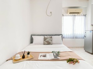 Une chambre d’hôtel bien rangée, avec un lit, un plateau sur lequel se trouvent une plante, un livre et un petit objet décoratif.