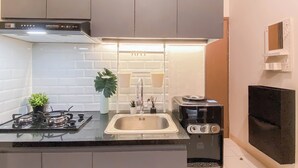 A modern kitchen with a gas stove, stainless steel sink, and a black electric kettle. - Standard 2Br At Podomoro Golf View Apartment (Gunung Putri)