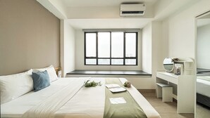Habitación de hotel con cama, escritorio, ventana y vista a la ciudad, y aire acondicionado.