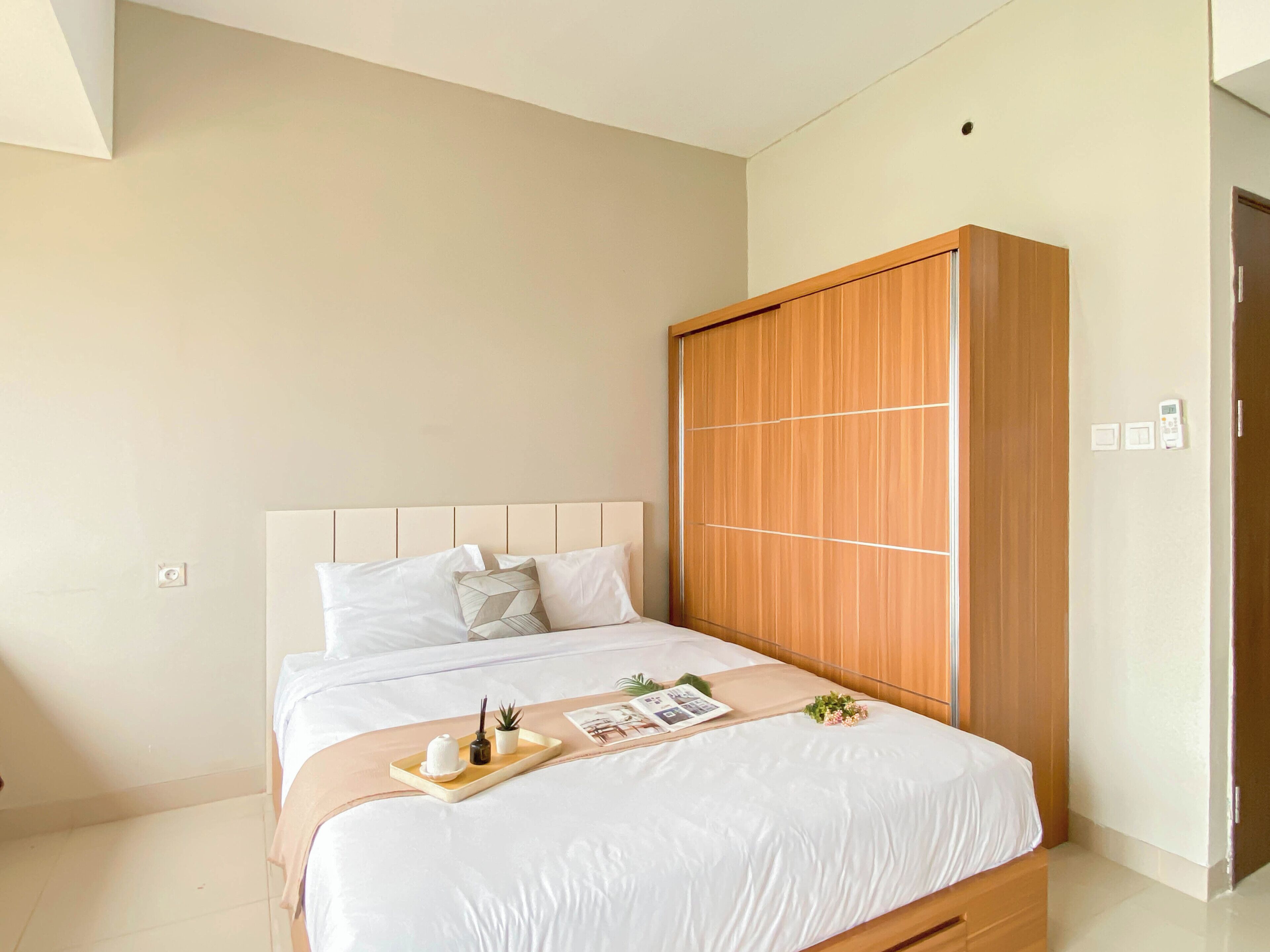 Un dormitorio con cama, armario de madera y mesita de noche con bandeja.