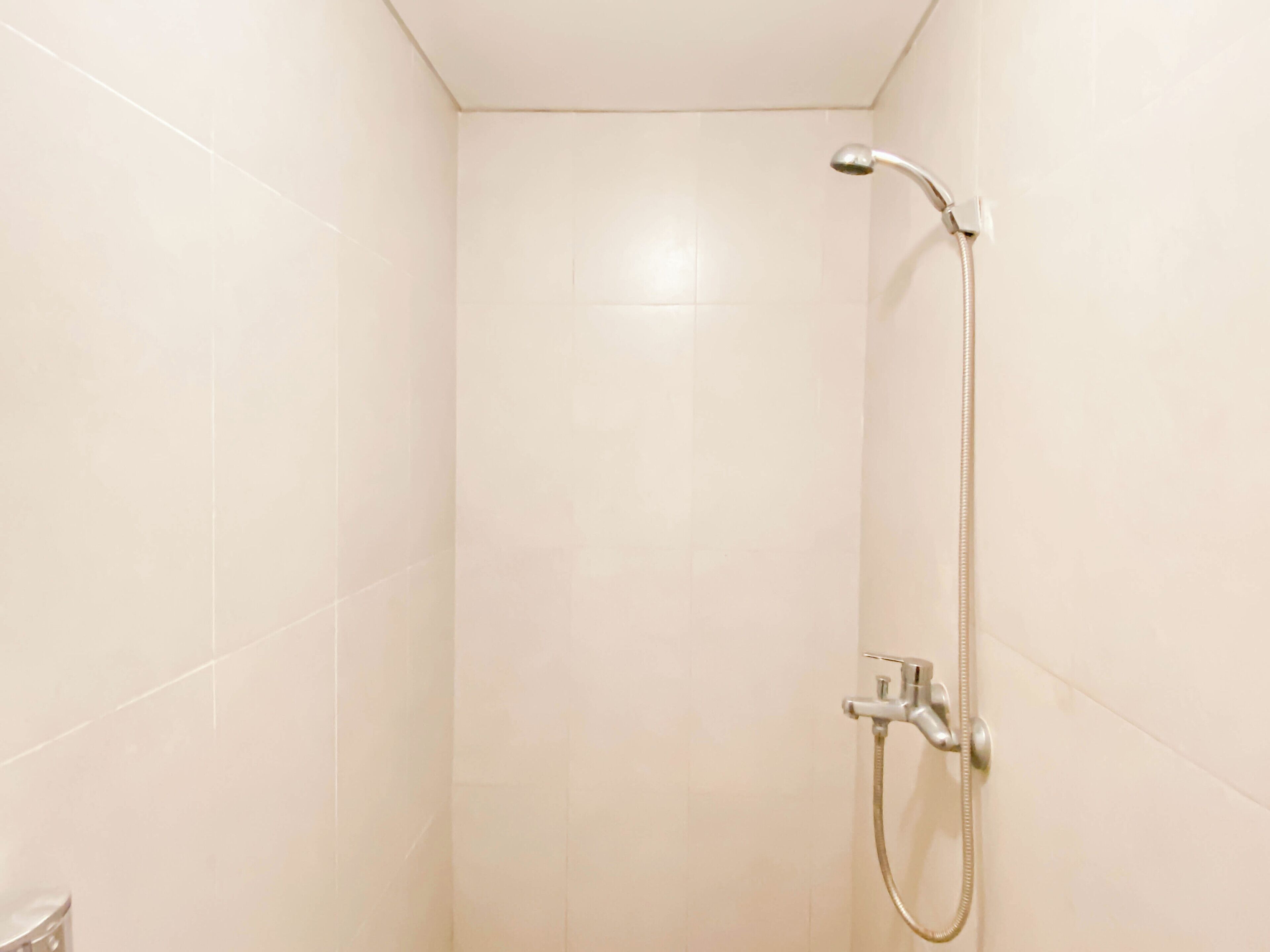 Un baño con ducha, paredes de azulejos y un inodoro.