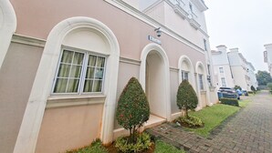 A row of white buildings with arched windows and a sign reading "Apartment 12". - Modern 4Br Apartment At Guest House Vanya Park (Pagedangan)