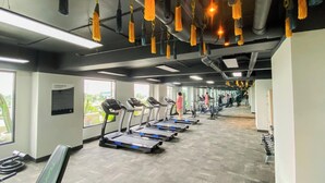 A gym with treadmills aligned along the wall, exercise equipment, and large windows. - Homey Studio At Sky House Alam Sutera Apartment (Tangerang)