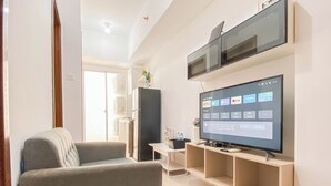 Un salon moderne avec un téléviseur à écran plat fixé au mur, un canapé gris et un design minimaliste.