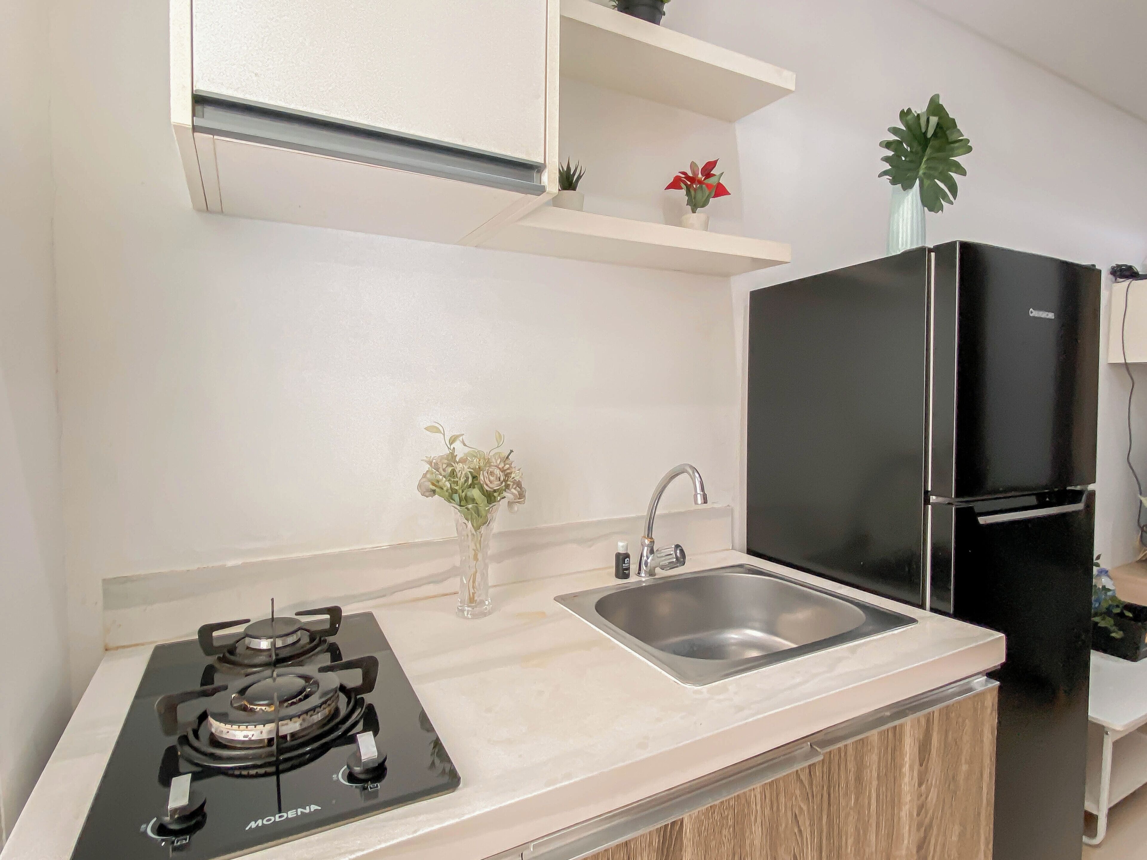 A modern kitchen with a gas stove, stainless steel sink, and a black refrigerator.