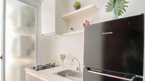 Une cuisine moderne avec un réfrigérateur noir, un évier en acier inoxydable et des armoires en bois.