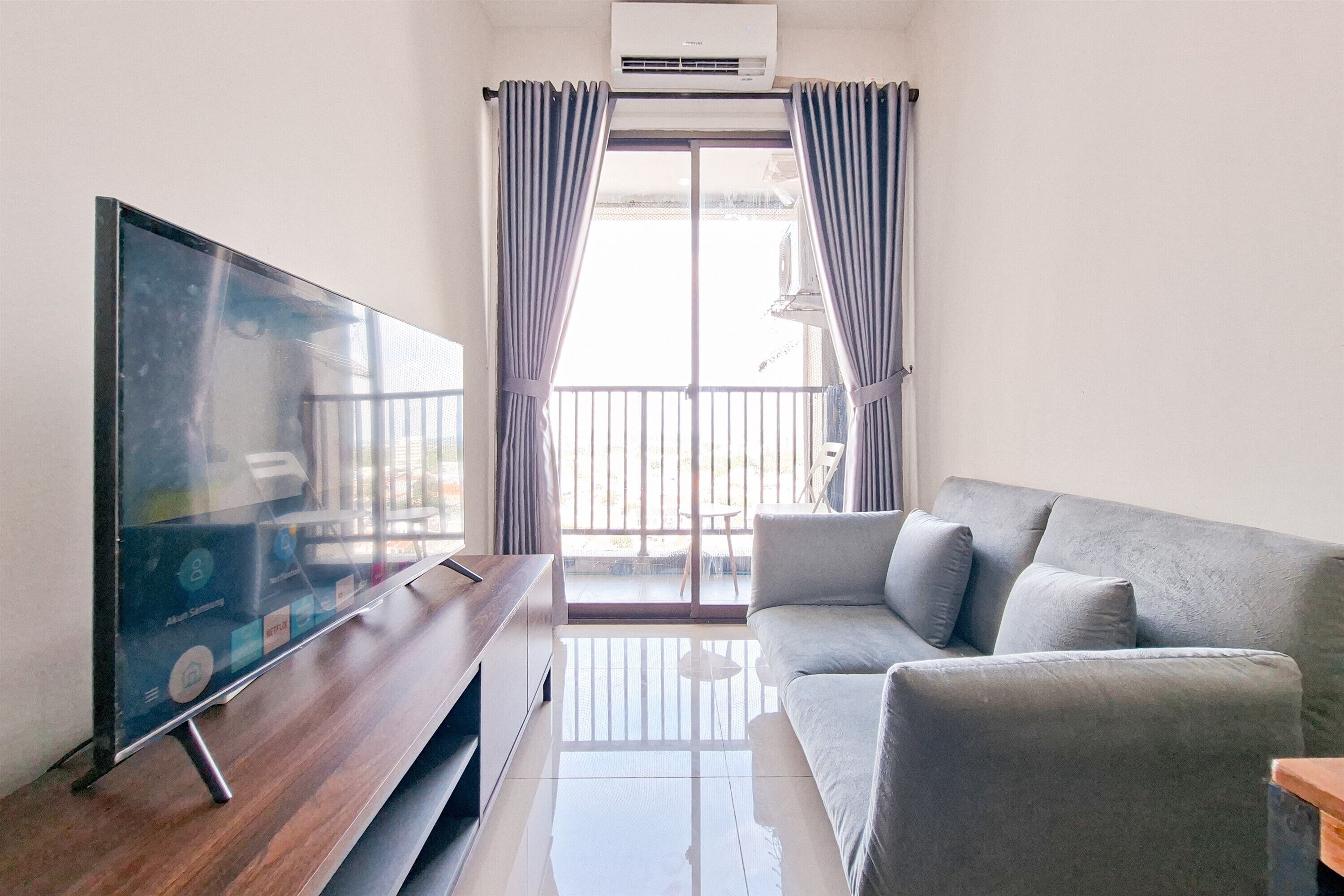 A modern living room with a flat-screen TV, grey sofa, and a wooden coffee table.