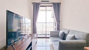 A modern living room with a flat-screen TV, grey sofa, and a wooden coffee table. - Trendy 1Br Apartment At Anwa Residence (South Tangerang)