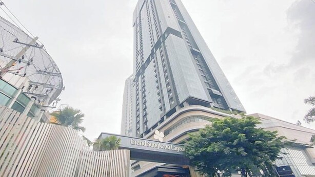 A tall, modern building with a sign reading "Grand Sungkono Lagoon." - Cozy And Homey 2Br At Grand Sungkono Lagoon Apartment (Surabaya)