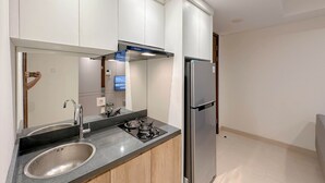 A modern kitchen with a stainless steel sink, a gas stove, a built-in oven, and a refrigerator. - Cozy And Homey 2Br At Grand Sungkono Lagoon Apartment (Surabaya)