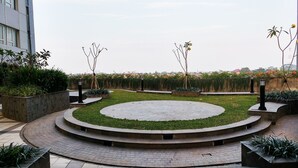 A landscaped courtyard with a circular central area, surrounded by low walls and various plants. - Basic Style And Homey 2Br At Apartment Nifarro Park (Jakarta)